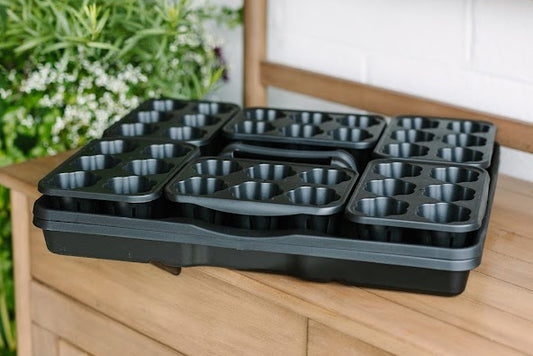 A set of black GreenStalk seed starters, placed on a wooden surface.